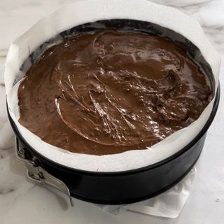Una tortiera riempita di glassa al cioccolato su carta oleata