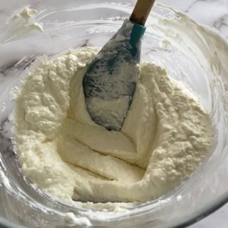 Una ciotola di panna montata con una spatola dentro.