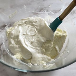 Una ciotola di panna montata con una spatola dentro.