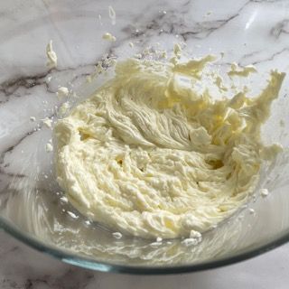 Una ciotola di vetro piena di panna montata su un tavolo.