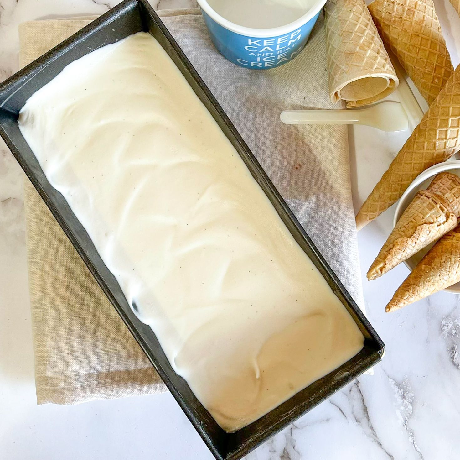 Una vaschetta di gelato accanto a una ciotola di gelato e coni gelato
