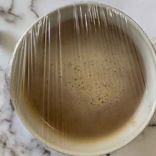 Una tazza di caffè avvolta nella pellicola trasparente su un tavolo.