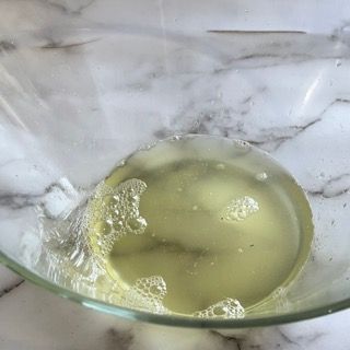 Primo piano di una ciotola di vetro piena di liquido su un tavolo.