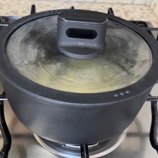 Una pentola con un coperchio di vetro è posta sopra un fornello.