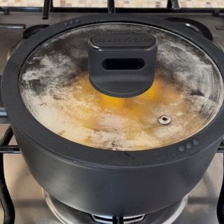 Una pentola con un coperchio di vetro sta cuocendo su un fornello