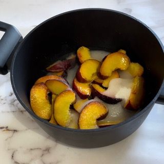 Un vaso nero pieno di pesche tagliate a fette su un tavolo