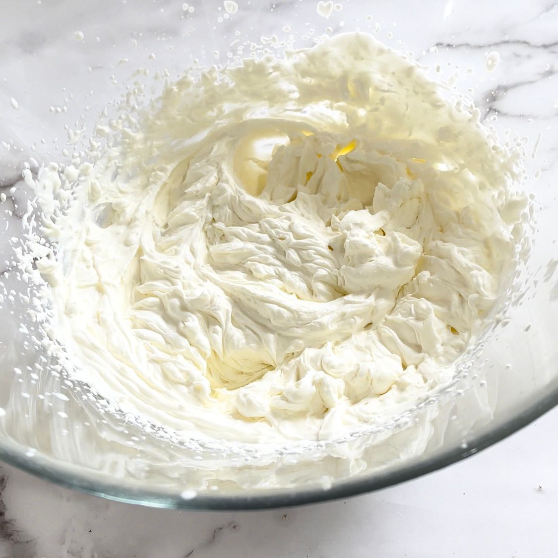 Panna montata in una ciotola di vetro su un tavolo.