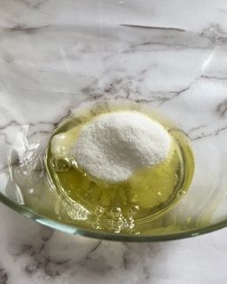 Una ciotola di vetro piena di liquido e zucchero su un tavolo.