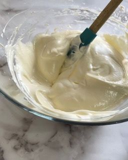 Una ciotola di panna montata con una spatola dentro.