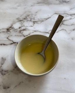 Una ciotola di liquido con un cucchiaio dentro su un tavolo.