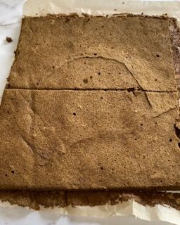 Un pezzo di brownie è appoggiato su un foglio di carta oleata.