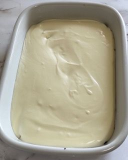 Una pirofila bianca piena di glassa bianca su un tavolo.