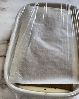 Una teglia ricoperta di pellicola trasparente e carta oleata.