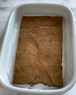 Una teglia bianca riempita con un pezzo di pane integrale.