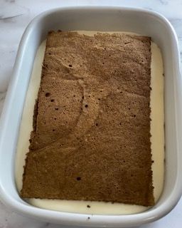 Un pezzo di torta è appoggiato su una teglia bianca.