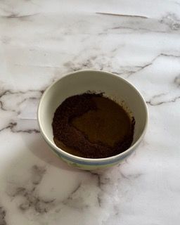 Una ciotola di polvere di caffè è appoggiata su un tavolo di marmo.
