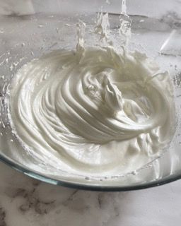 Primo piano di una ciotola di panna montata su un tavolo.