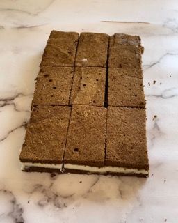 Una fetta di torta viene tagliata a quadrati su una superficie di marmo.