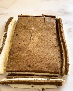 Una casetta di pan di zenzero viene tagliata a pezzi e impilata l'una sull'altra su un tavolo.