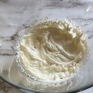 Primo piano di una ciotola di panna montata su un tavolo.