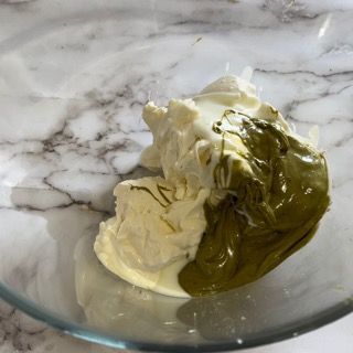 Una ciotola di vetro piena di formaggio cremoso e salsa verde