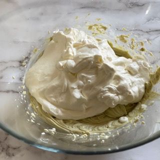 Una ciotola di vetro piena di panna montata su un tavolo.