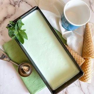 Un vassoio di gelato alla menta accanto a un cono waffle e una tazza