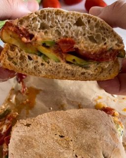 Una persona tiene in mano un panino mezzo mangiato