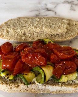 Un primo piano di un panino con pomodori e zucchine su un tavolo.
