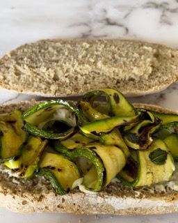 Un primo piano di un panino con le zucchine su un tavolo.