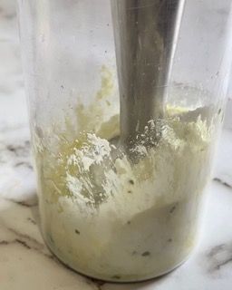 Si usa un frullatore per mescolare una salsa in una tazza.