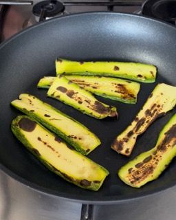 Una padella piena di zucchine affettate su un fornello