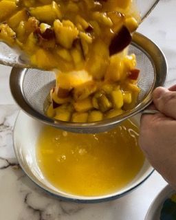 Una persona versa il cibo in una ciotola attraverso un colino.