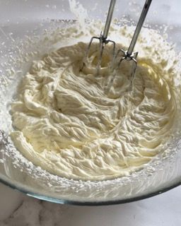 Una ciotola di panna montata con uno sbattitore dentro.