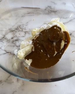 Una ciotola di vetro piena di un liquido marrone e un pezzo di formaggio.