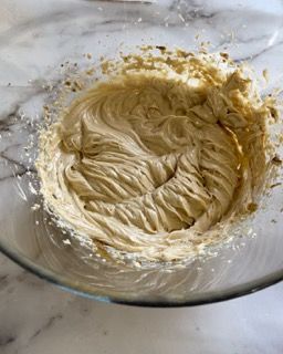 Una ciotola di vetro piena di panna montata su un tavolo.
