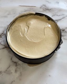 Una tortiera piena di impasto è appoggiata su un tavolo.