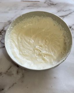 Una ciotola di panna montata è appoggiata su un tavolo.
