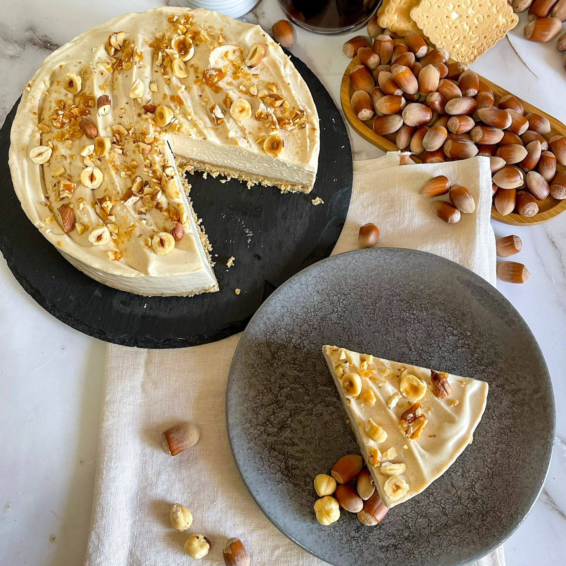 Una fetta di cheesecake è su un piatto accanto a una torta su un tavolo.