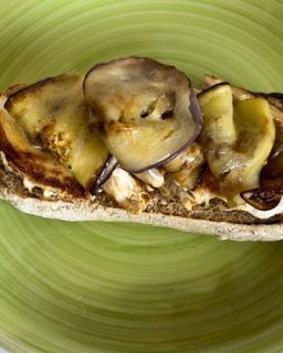 Un piatto verde con sopra un panino con melanzane e formaggio.