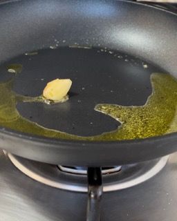 Un pezzo di burro si scioglie in una padella sul fornello.