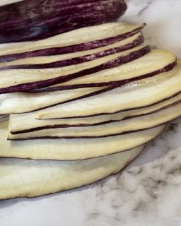 Una pila di melanzane a fette su una superficie di marmo