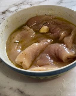 Una ciotola di petti di pollo con un pezzo di aglio dentro