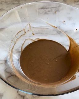 Una ciotola di vetro piena di liquido marrone su un tavolo