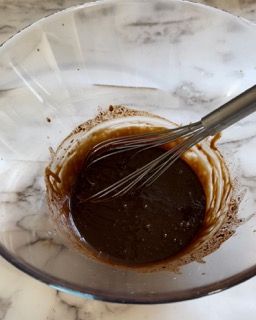 Una frusta è in una ciotola di liquido marrone