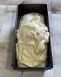 Uno stampo da plumcake riempito di glassa bianca su un tavolo