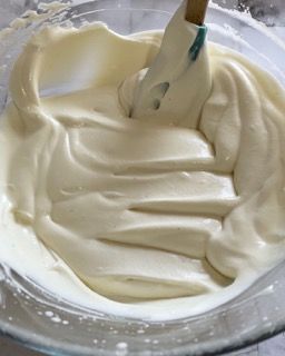 Una ciotola di glassa bianca con una spatola dentro.