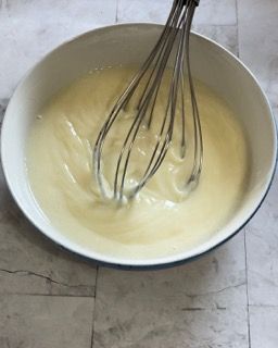 Una ciotola di panna montata con una frusta dentro.