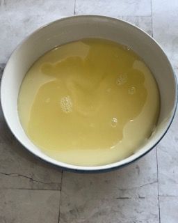 Una ciotola piena di liquido giallo è appoggiata su un tavolo.