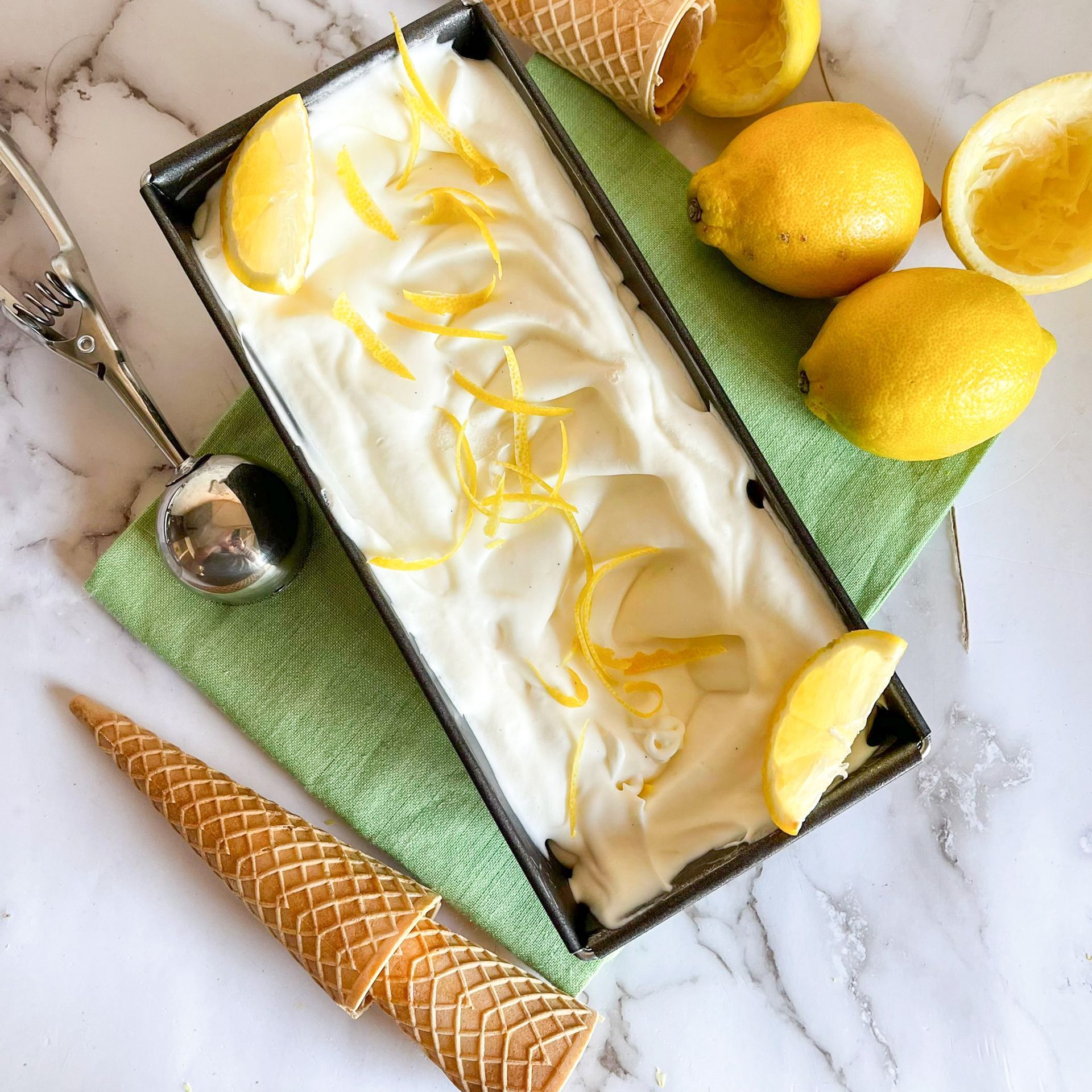 Un contenitore di gelato con scorza di limone e un cono di cialda su un tavolo.